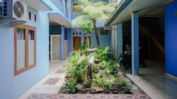 A multi-level building with a central courtyard featuring potted plants and a small fountain. - Hotel O Guest House Amalia Malang (Malang)