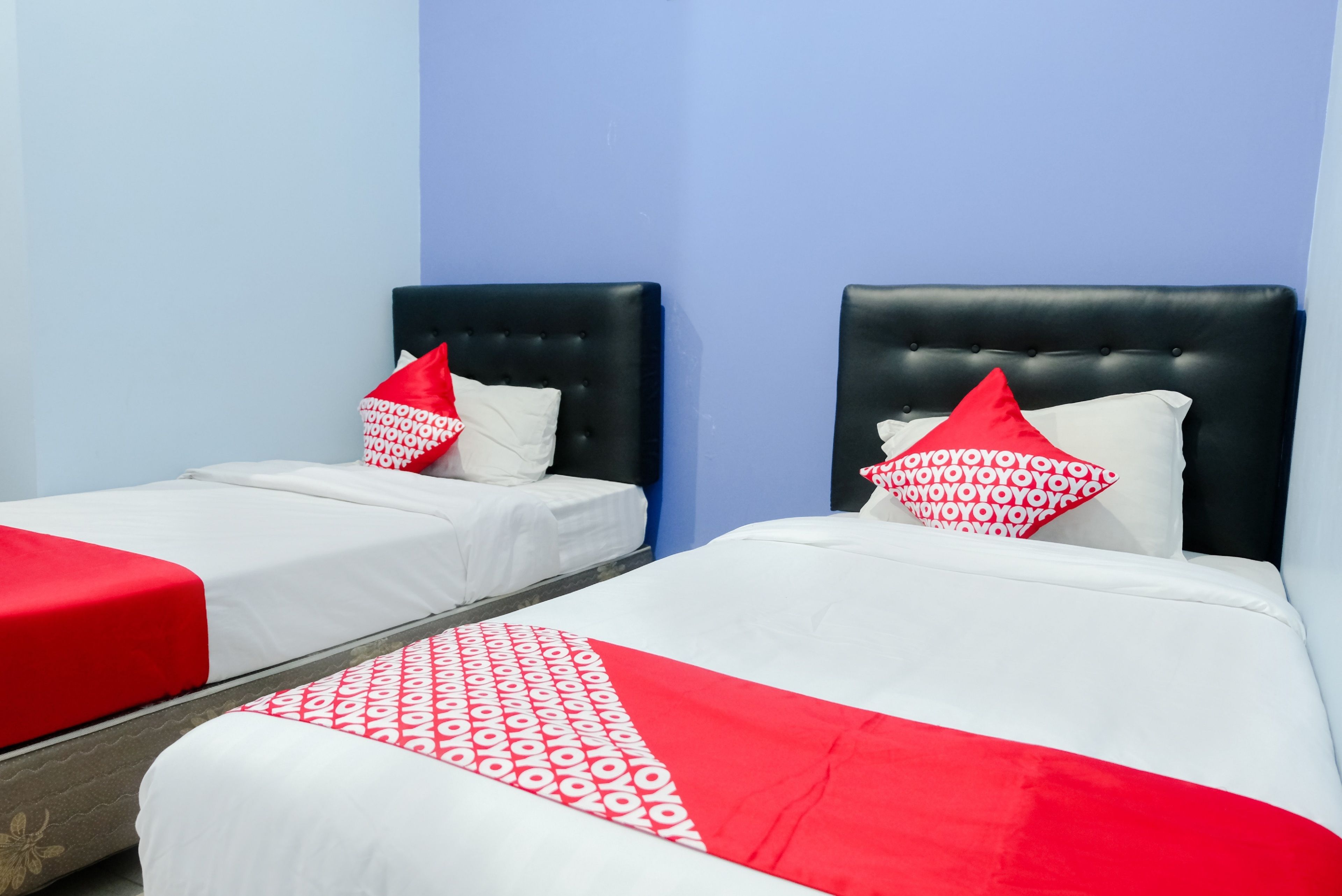 Two single beds with black headboards, white bedding, and red accents.