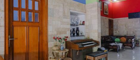 A room with a wooden door, a piano, a small table, and a sofa.