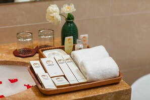 A tray with toiletries, a towel, and a vase with flowers on a bathroom counter. -  Nesta Hotel Saigon (Ho Chi Minh City)
