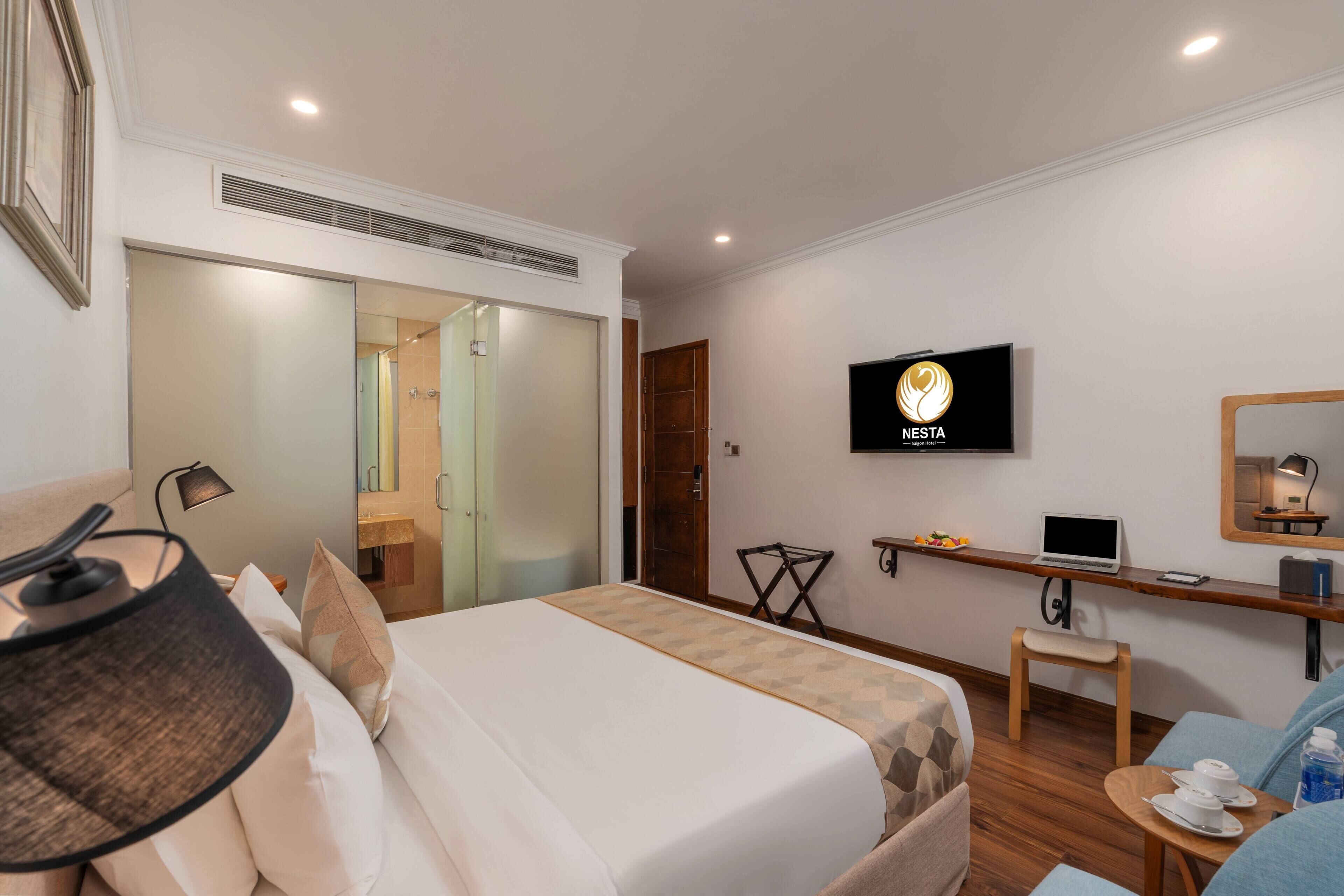 Hotelkamer met een bed, bureau, televisie, stoel en een klein tafeltje met een laptop en telefoon.