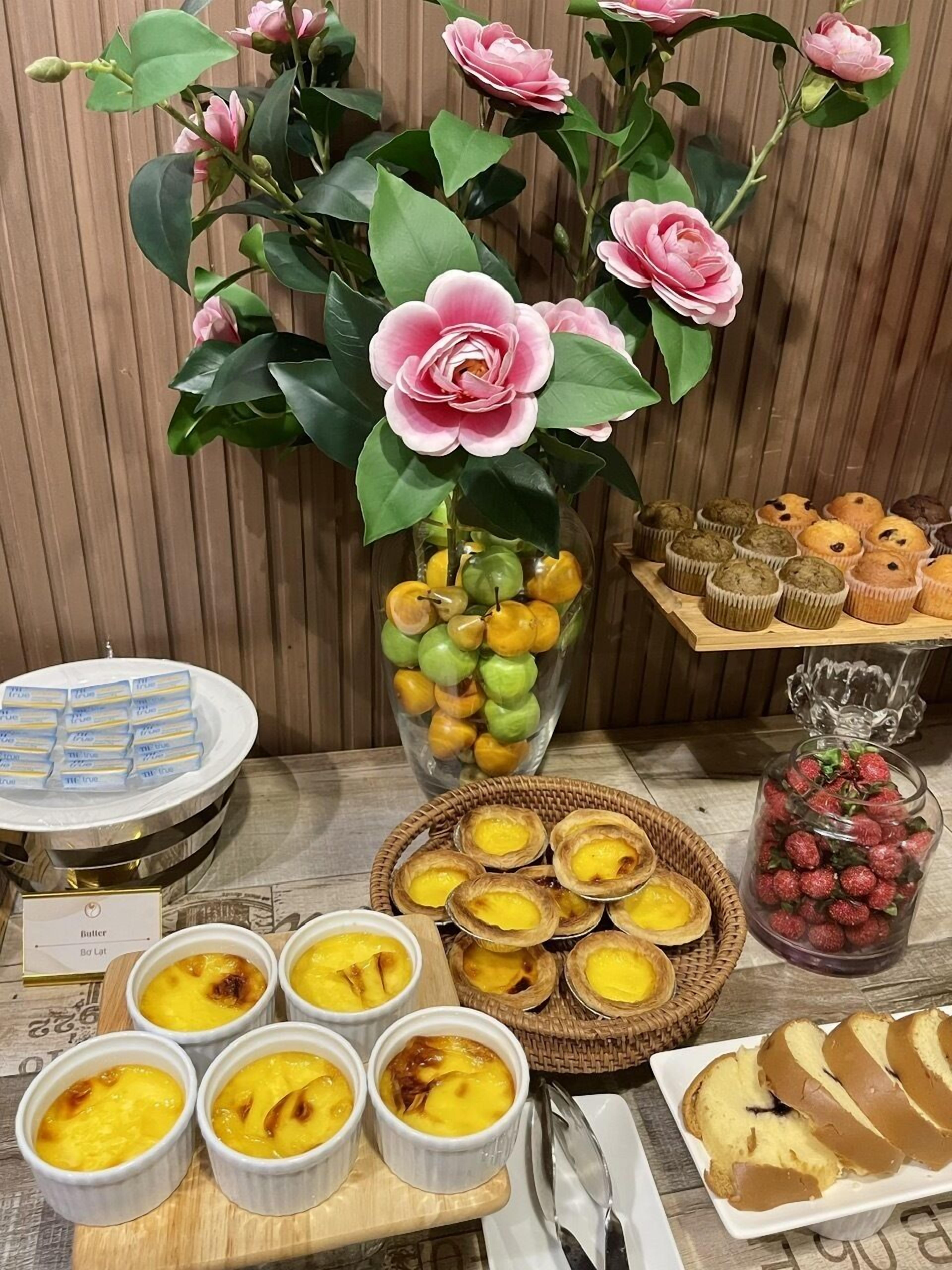 A table with various pastries, a bouquet of flowers, and a sign indicating a butter and bread option.