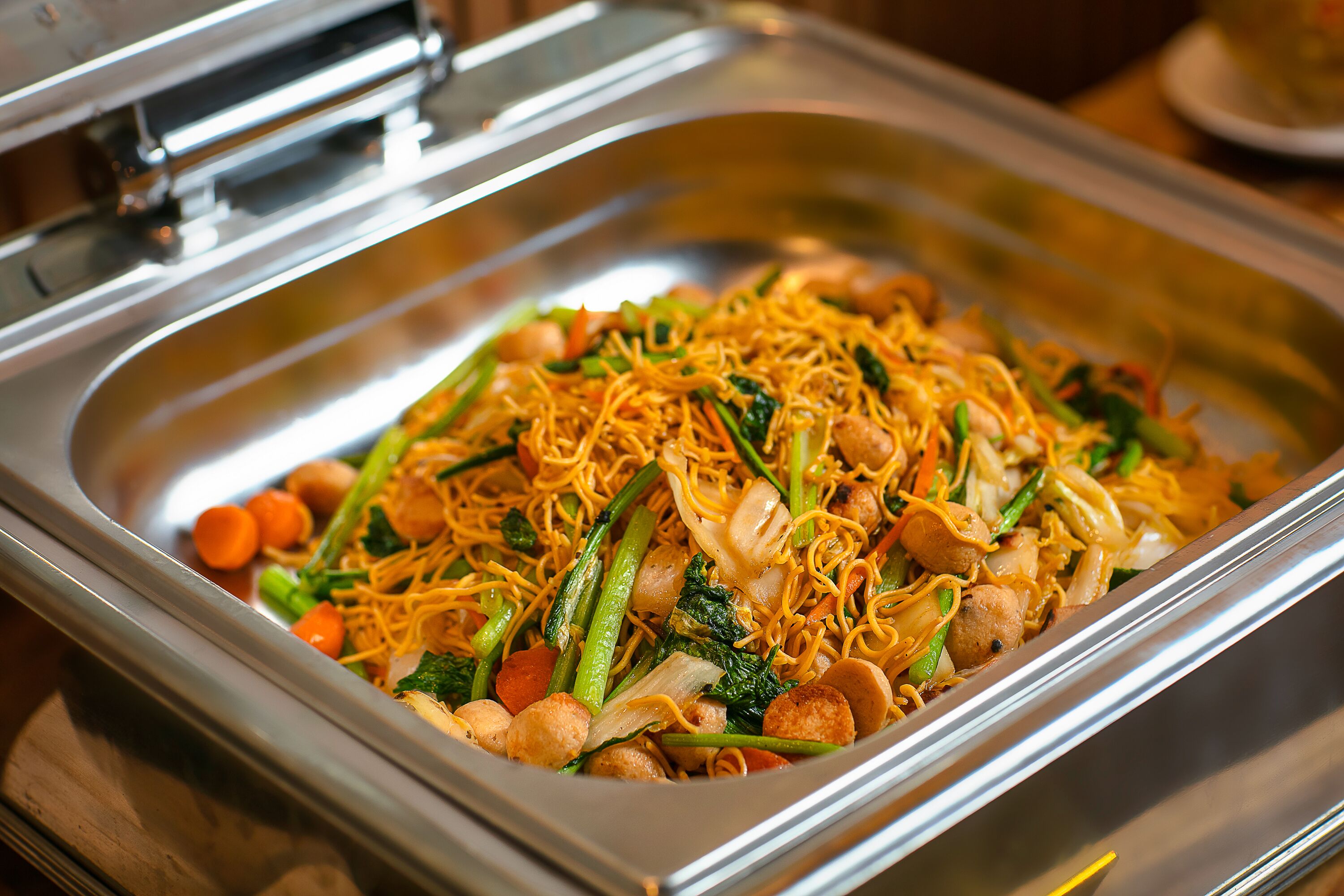 Un buffet proposant une variété de plats, notamment des nouilles, des légumes et de la viande.