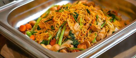 Un buffet proposant une variété de plats, notamment des nouilles, des légumes et de la viande.