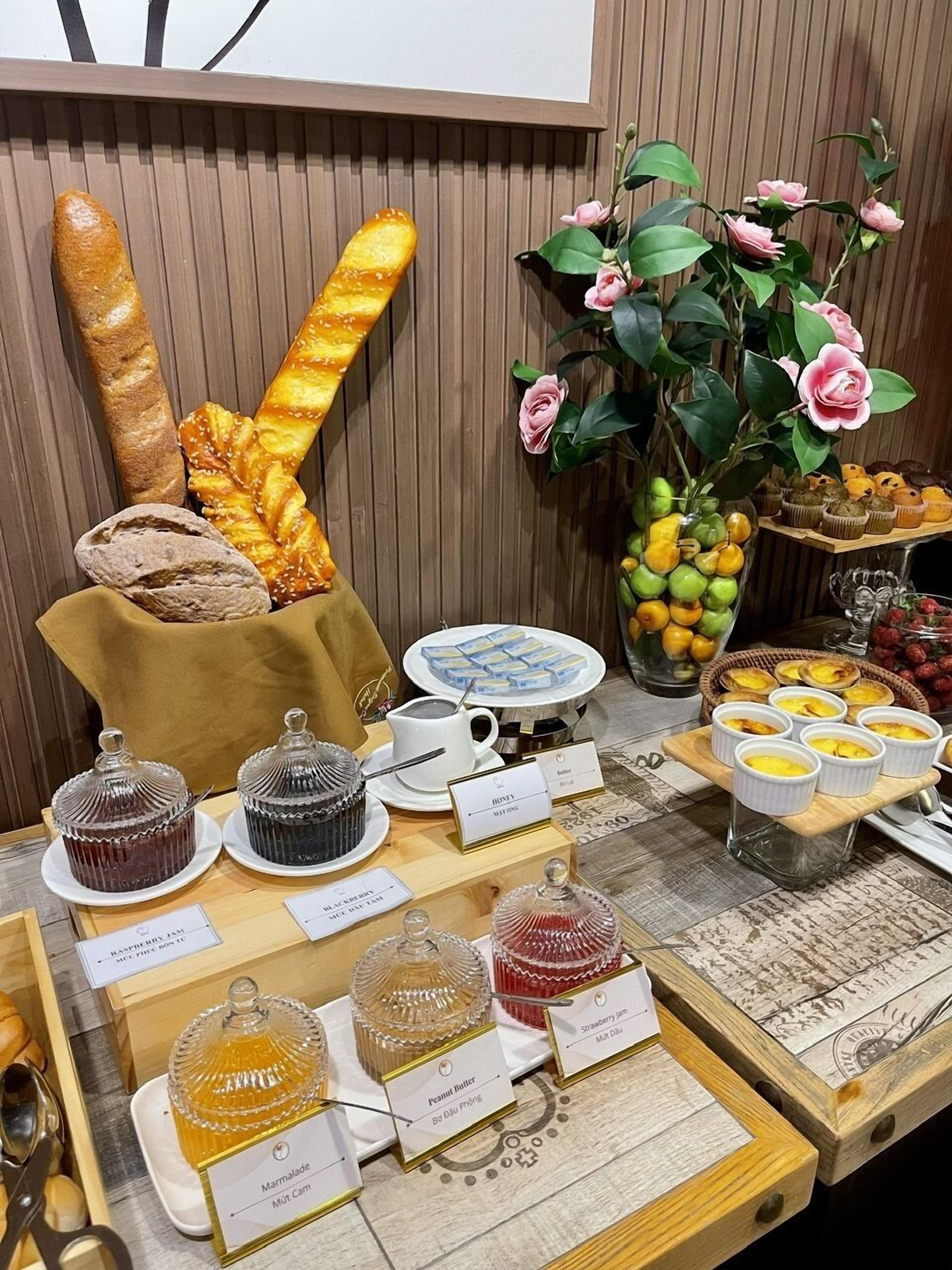 A breakfast buffet with various pastries, jams, and a decorative plant.