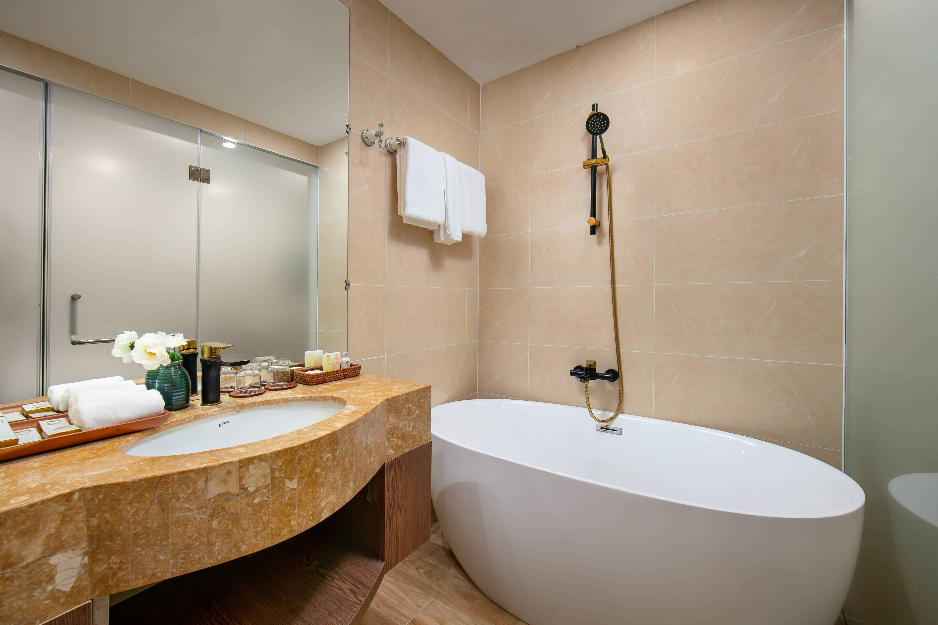 A bathroom with a large bathtub, a vanity with a sink, and a mirror.
