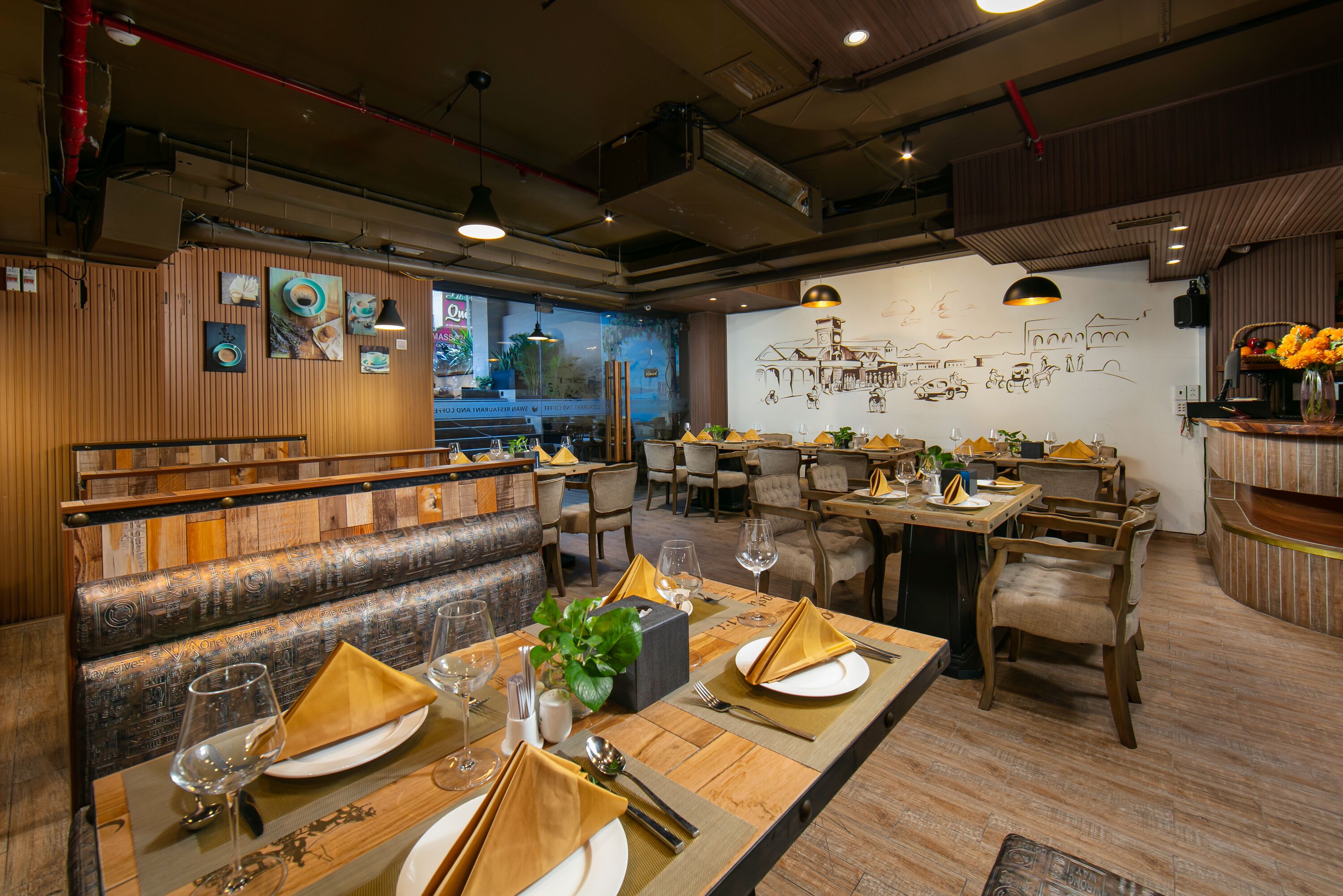 Un restaurante con muebles de madera, mesas dispuestas con platos, vasos y servilletas.