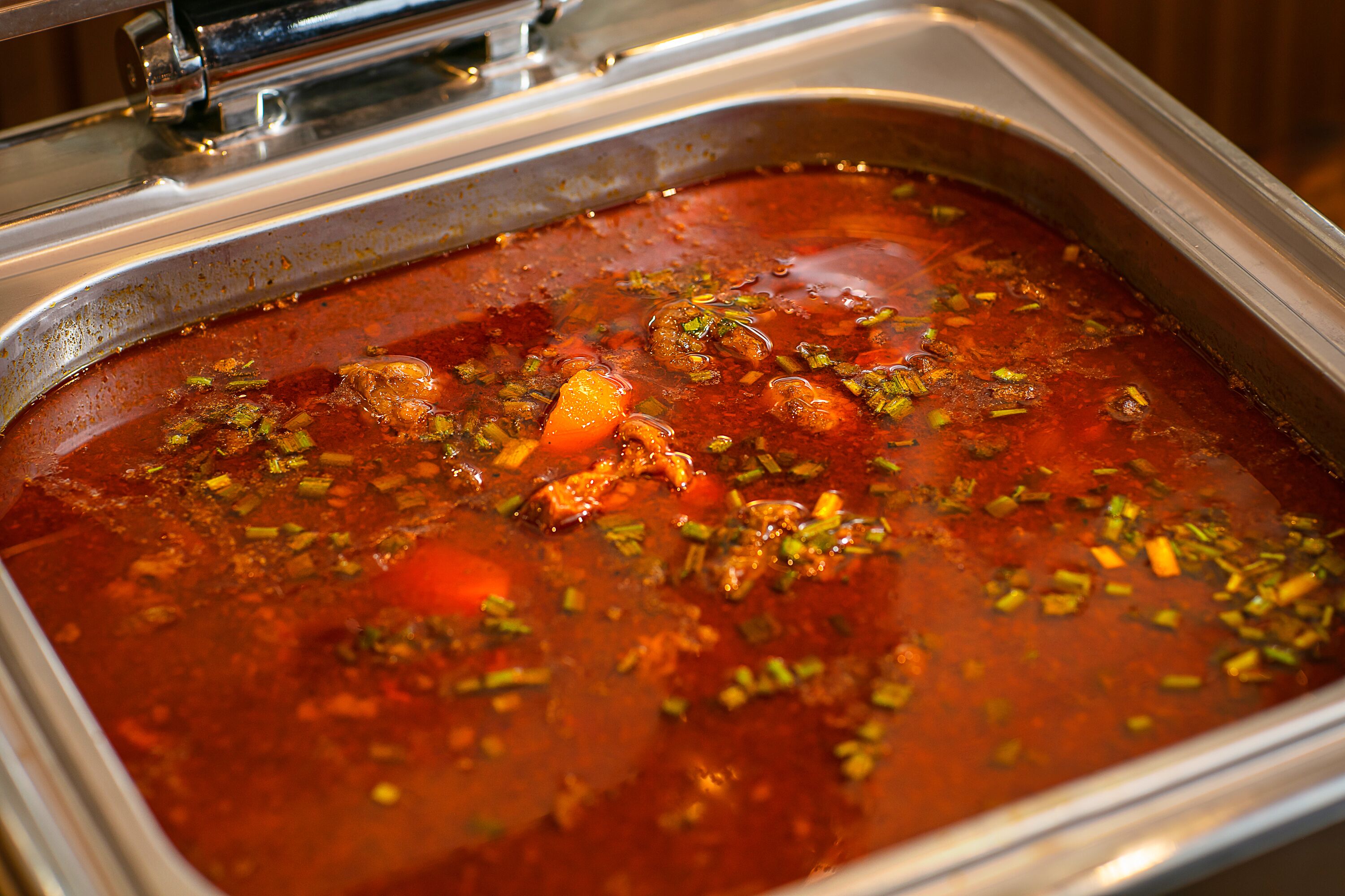 Un bufé con una variedad de platos, incluyendo un guiso rojo con carne y verduras.