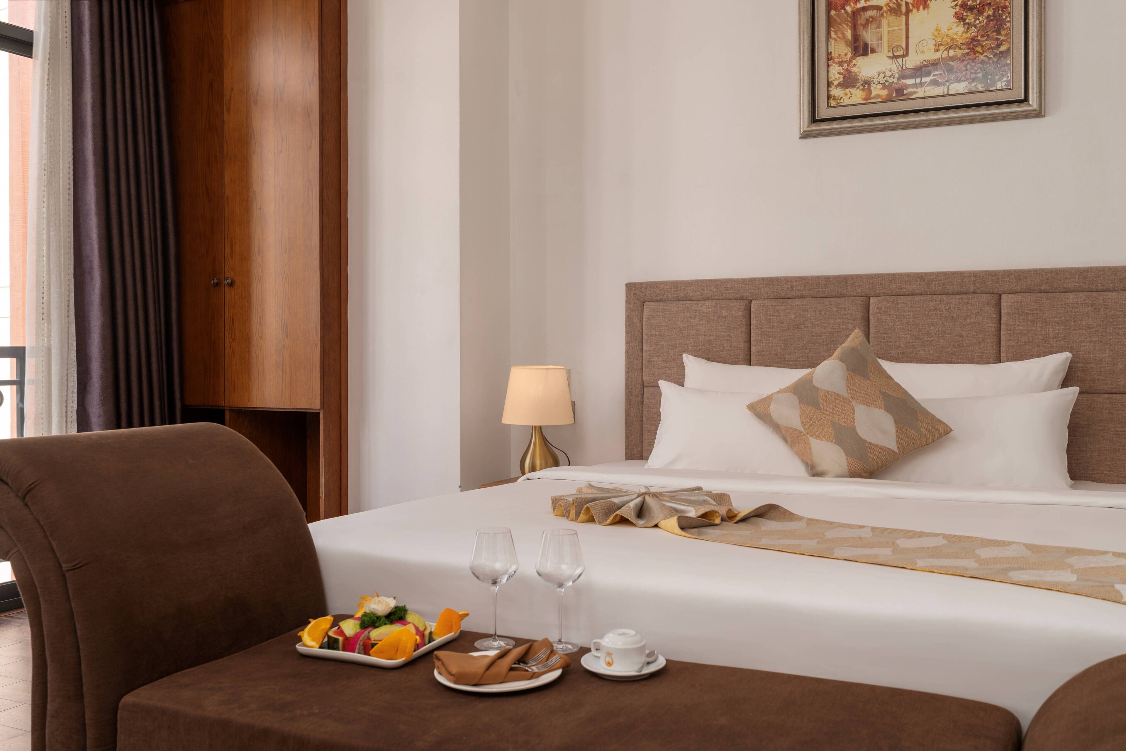 Una camera d'albergo con un letto, un tavolo per la colazione, una lampada e un quadro appeso al muro.
