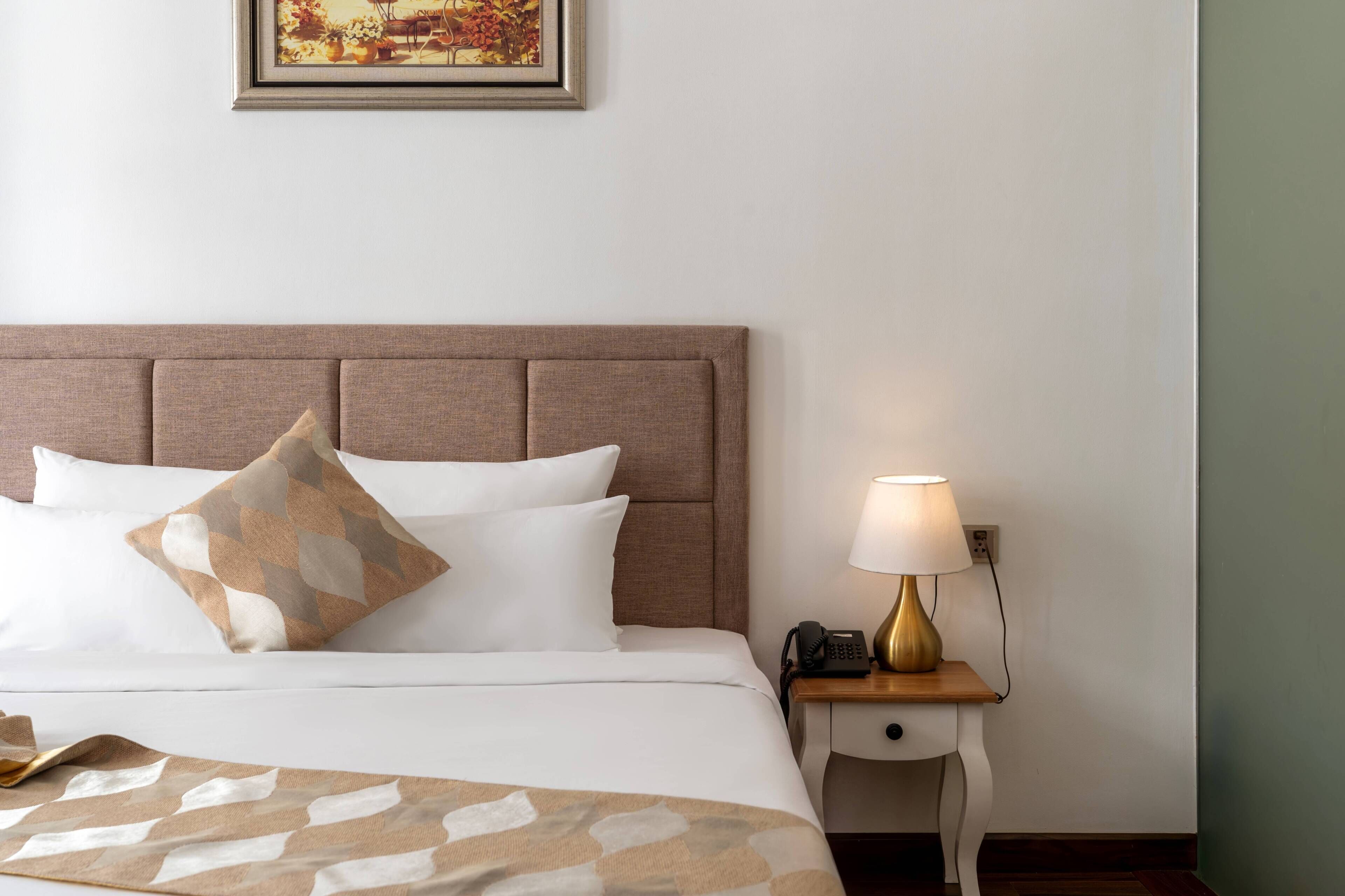 A neatly made bed with a patterned throw, a bedside lamp, and a telephone on a nightstand.