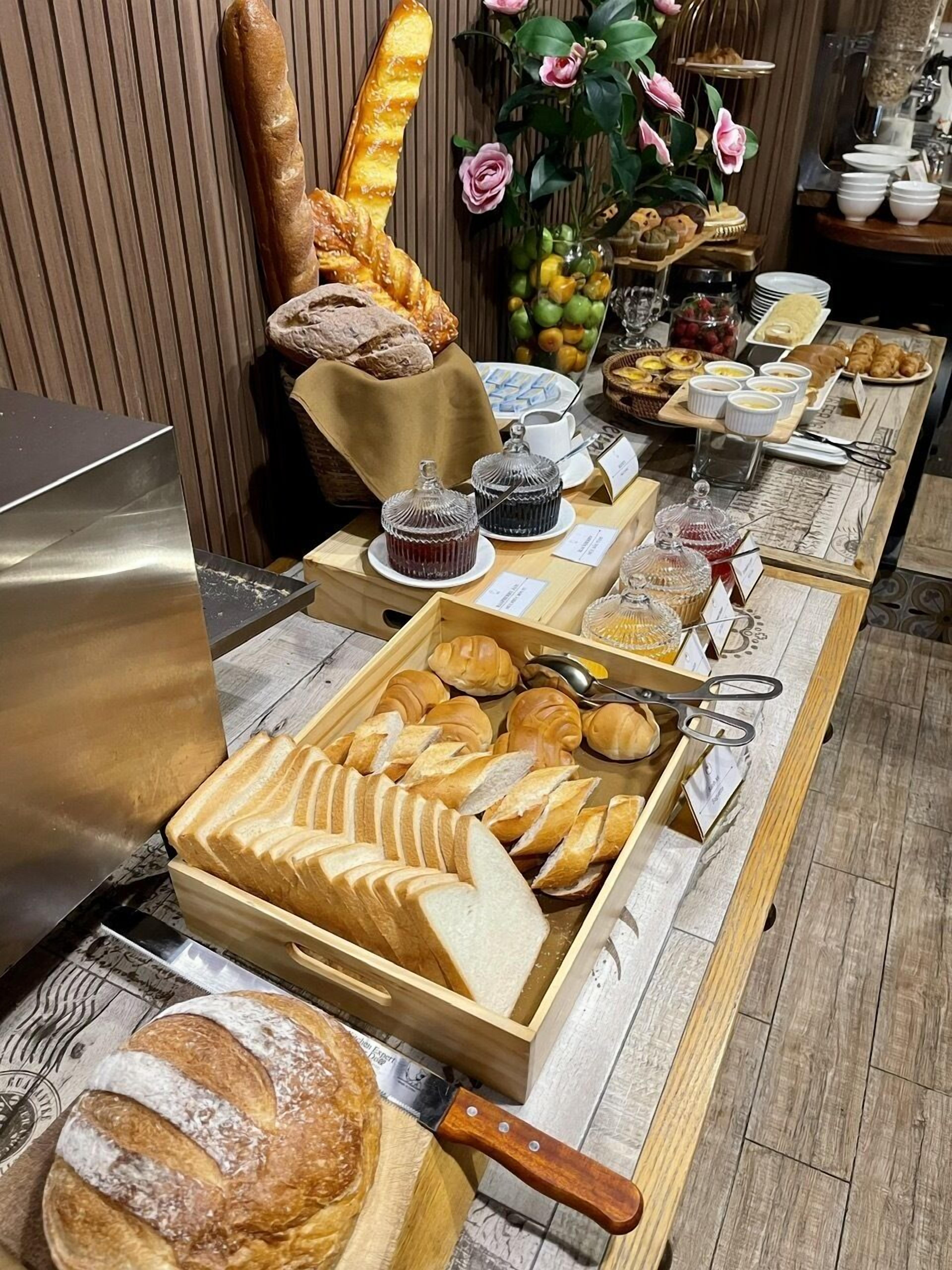 Un buffet proposant une variété de pains, de viennoiseries et de condiments.