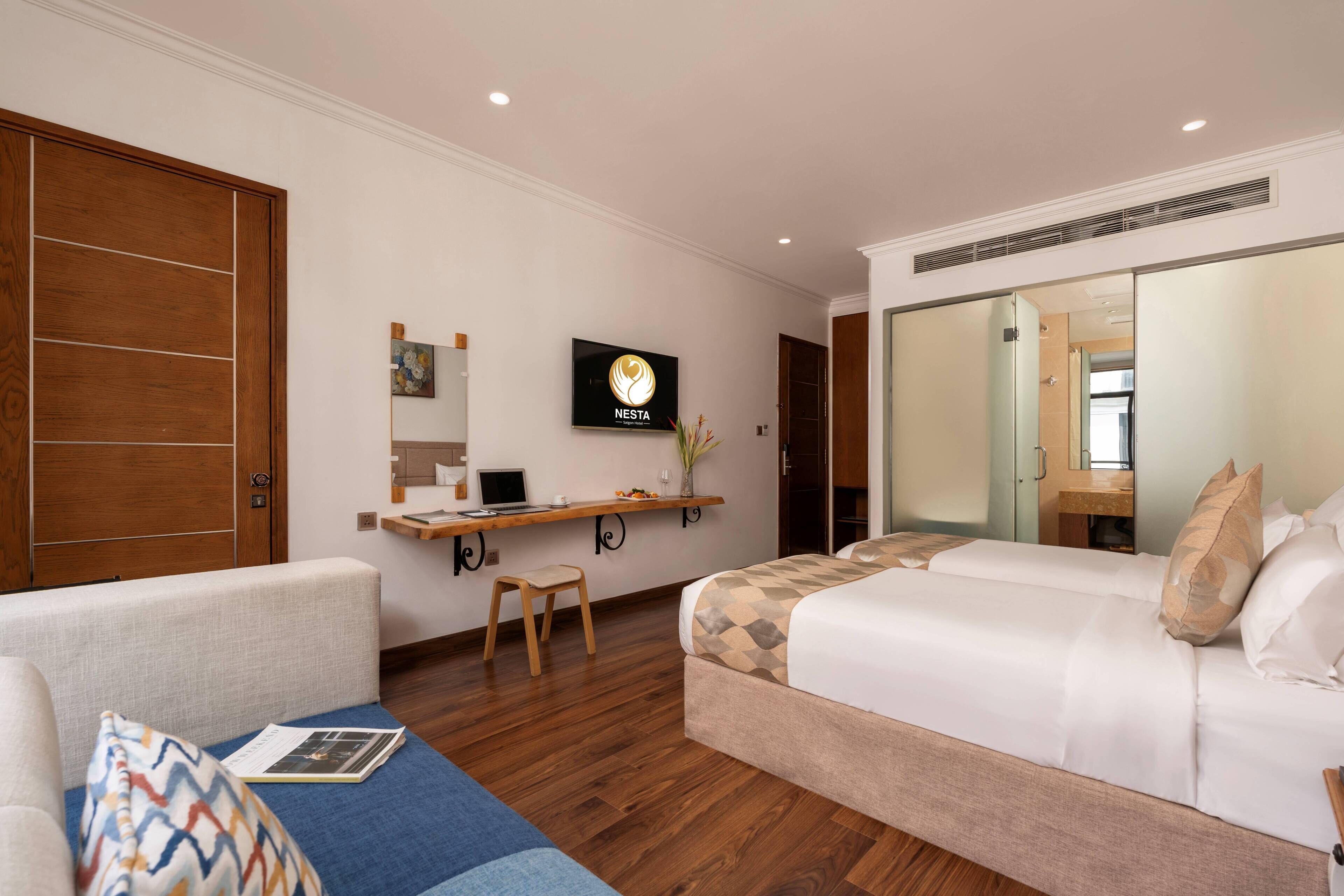 A hotel room with a bed, a desk with a computer, a chair, a TV on the wall, and a wardrobe.