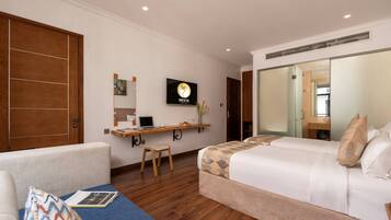 A hotel room with a bed, a desk with a computer, a chair, a TV on the wall, and a wardrobe.