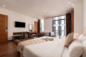 Ein Hotelzimmer mit Bett, Schreibtisch mit Computer, Fernseher und Balkon mit Blick.