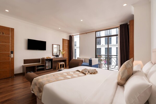 A hotel room with a bed, a desk with a computer, a TV, and a balcony with a view. -  Nesta Hotel Saigon (Ho Chi Minh City)