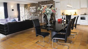Ein modernes Wohnzimmer mit Essbereich, Küche und Steinwand.