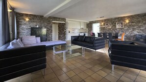 Ein modernes Wohnzimmer mit einem Sofa, einem Glastisch und einem schwarzen Ledersessel.