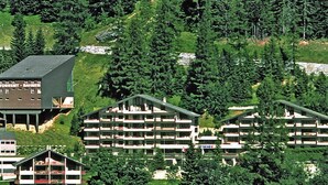 Ein mehrstöckiges Hotel mit flachem Dach, umgeben von üppiger Vegetation und Bäumen.
