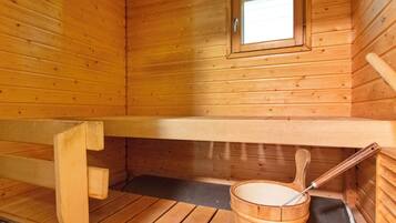 Un sauna de madera con un banco, un balde y una ventana.