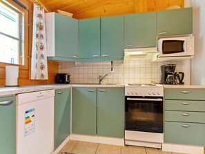 Una cocina con gabinetes verde azulado, un microondas blanco y una estufa.