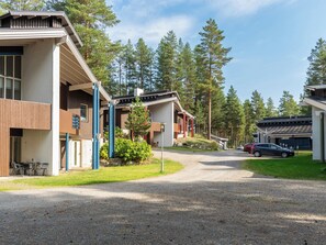 Asuinalue, jossa on moderneja taloja, sorapäällysteinen ajotie ja kauempana näkyvä pysäköity auto.