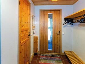 A hallway with wooden doors, a bench, and a hanging coat rack.