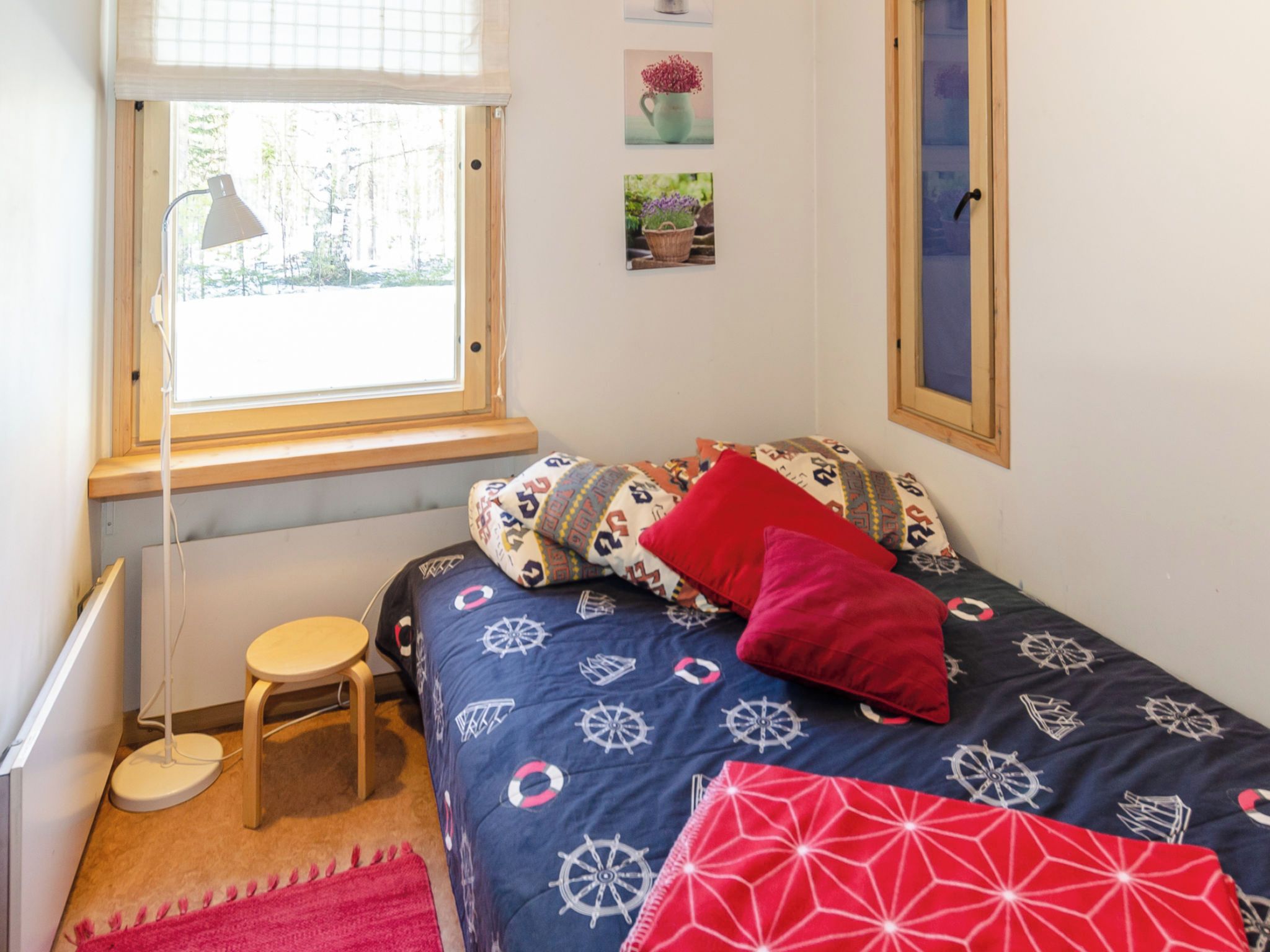 Ein Schlafzimmer mit einem Bett, einem kleinen Hocker, einem Schreibtisch und einem Fenster.