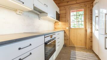 Una cucina moderna con mobili bianchi, forno integrato e soffitto in legno.