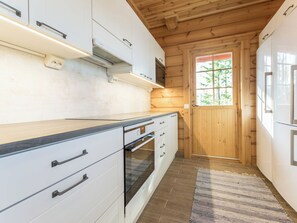 A modern kitchen with white cabinetry, a built-in oven, and a wooden ceiling. - Vacation home Telkkä by Interhome (Jämsä)