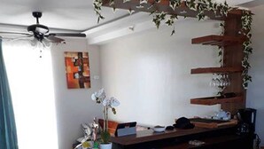 A compact kitchen with a refrigerator, a coffee machine, and a dining area with chairs and a table. - Simple & Cozy Accommodations (Lapu-Lapu)