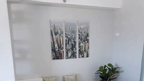 A modern living room with a sectional sofa, a potted plant, and abstract artwork on the wall. - Simple & Cozy Accommodations (Lapu-Lapu)