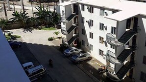 A multi-story building with balconies, parked cars, and a clear sky. - Simple & Cozy Accommodations (Lapu-Lapu)