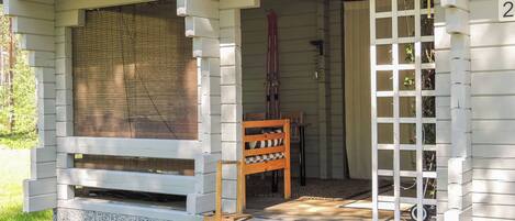 A porch with a wooden bench, a door, and a window with blinds.