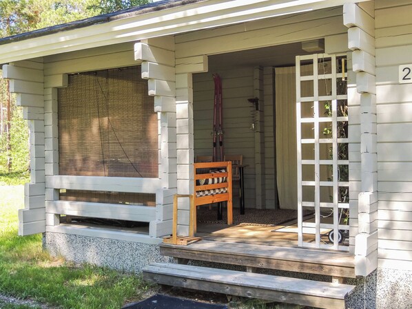 A porch with a wooden bench, a door, and a window with blinds.