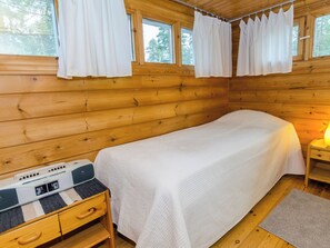 A single-bed cabin room with wooden walls, a bedside table with a lamp, and a Sony portable radio.