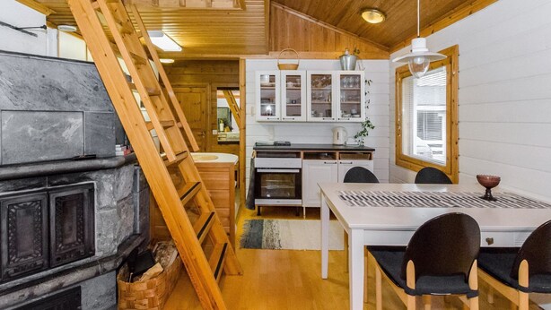 Una cocina compacta con armarios de madera, una estufa y un comedor con mesa y sillas.