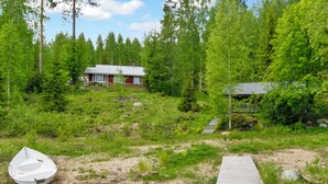 Eine Holzstele führt zu einem Haus, das von dichtem Wald umgeben ist.
