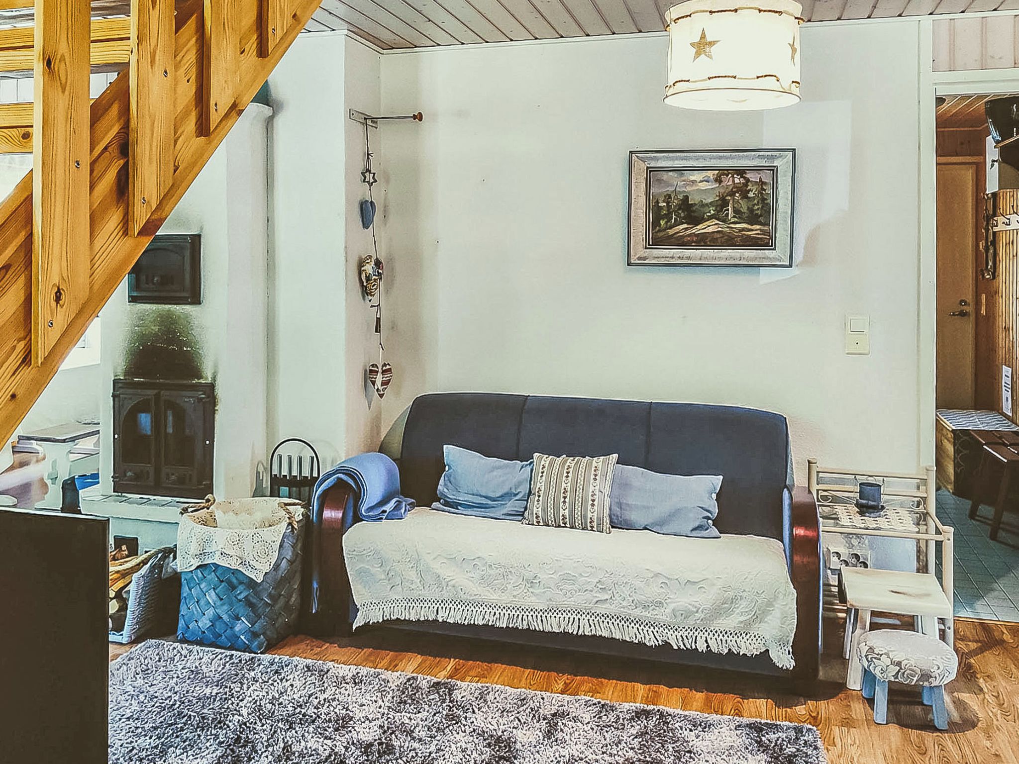 A cozy living room with a sofa, a small table, a chair, and a staircase.