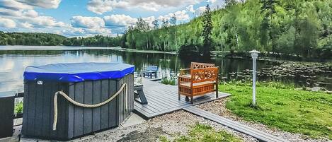 A hot tub on a dock with a wooden bench and a lamp post.