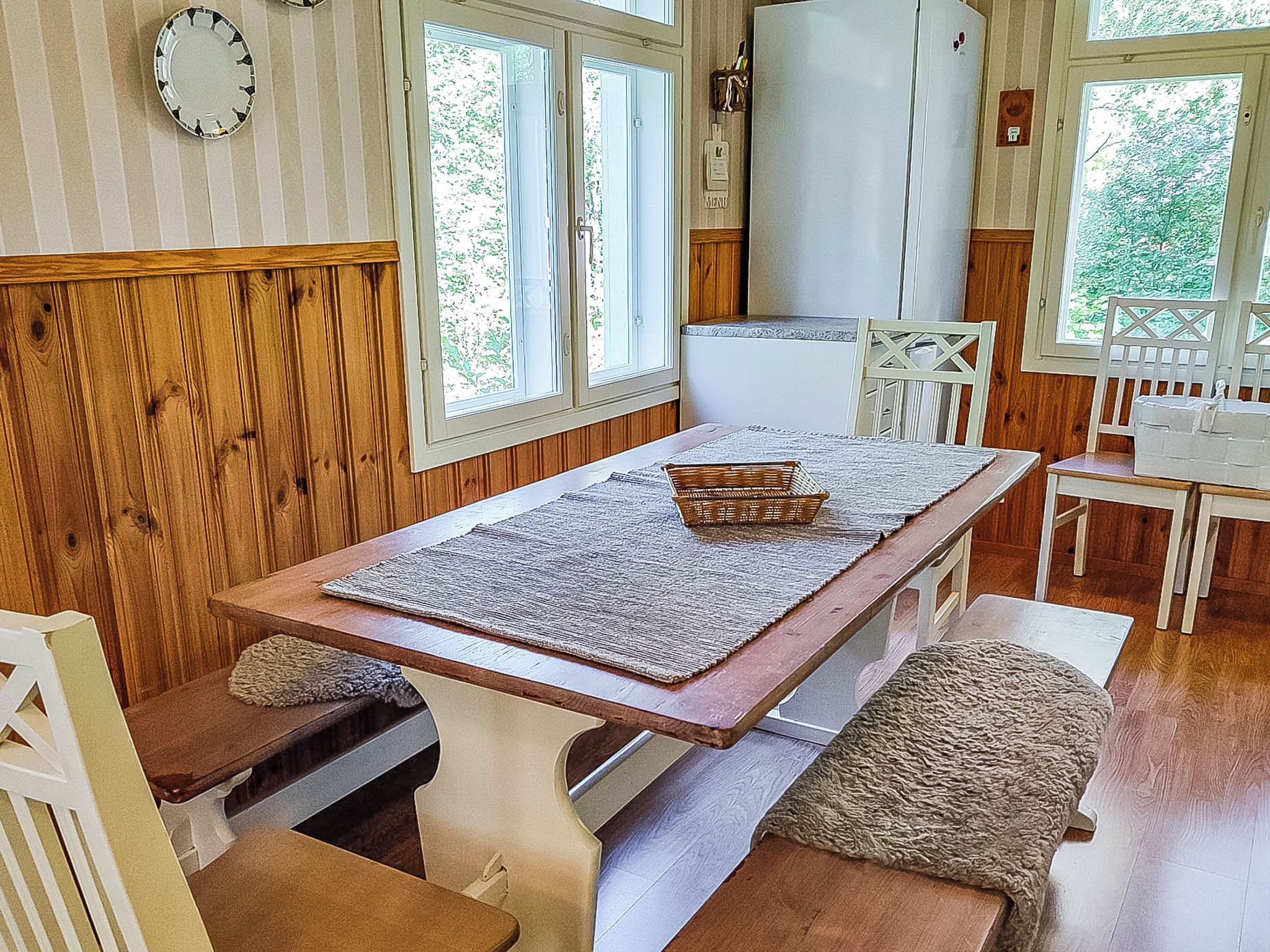Puisesta materiaalista valmistettu ruokailutila, jossa on pöytä, penkit ja tuolit.