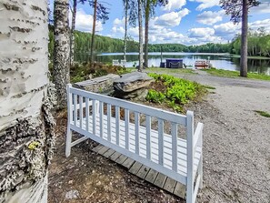 A wooden deck with a white railing, surrounded by birch trees and a lake view. - Villa ahomoisio by Interhome (Lavia)