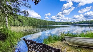 Un banc au bord d’un lac, avec un bateau à proximité.