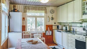 Une cuisine de taille réduite avec des meubles blancs, une cuisinière, un four à micro-ondes et un évier. On y trouve une table à manger avec des chaises et un tapis orné de motifs en forme d’étoiles.