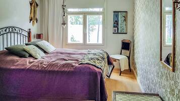Een slaapkamer met een bed, een stoel, een raam en een spiegel.