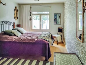 Ein Schlafzimmer mit Bett, Stuhl, Fenster und Spiegel.