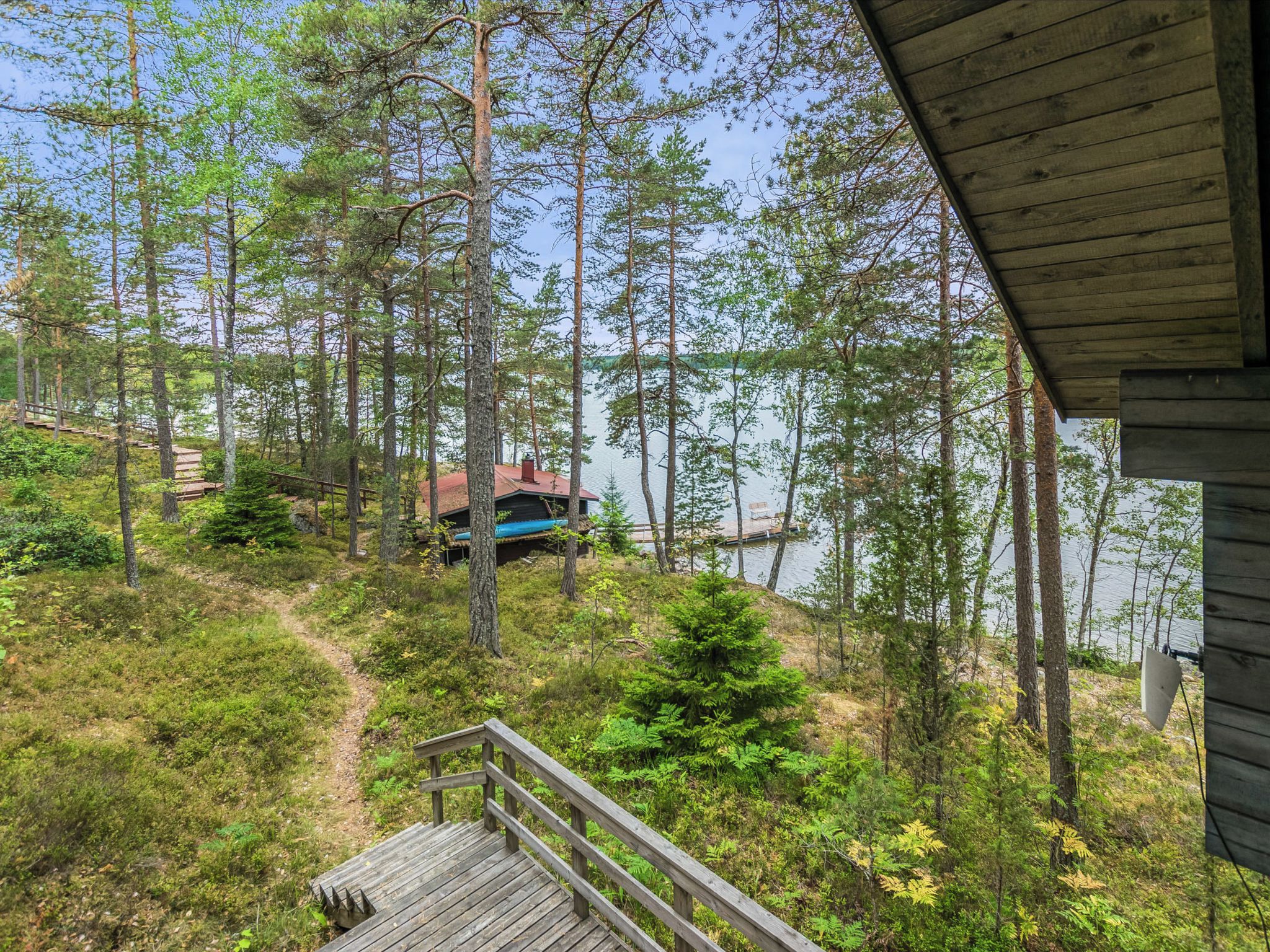 En hytte med terrasse med udsigt over skov og vand.