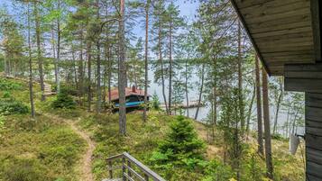 En hytte med terrasse med udsigt over skov og vand.