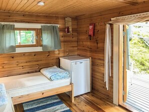 A small cabin with a single bed, a compact refrigerator, and a window with checkered curtains. - Ranta-iivari by Interhome (Lohja)