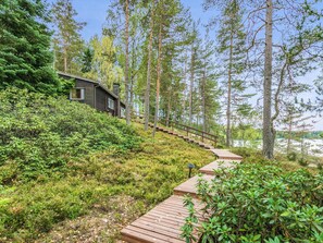 En trætrap fører op til en hytte omgivet af tæt skov.
