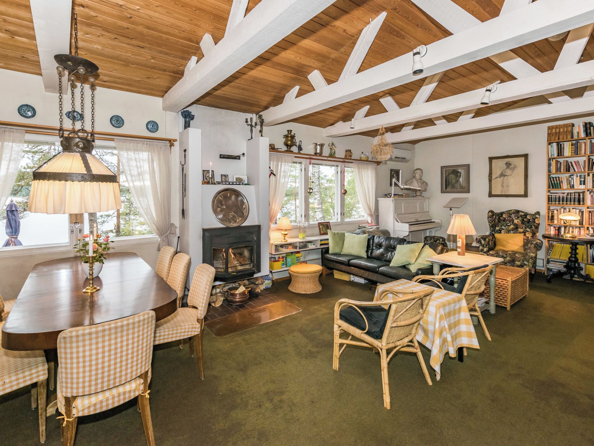 A cozy living room with a fireplace, a dining area with checkered chairs, and a bookshelf filled with books.